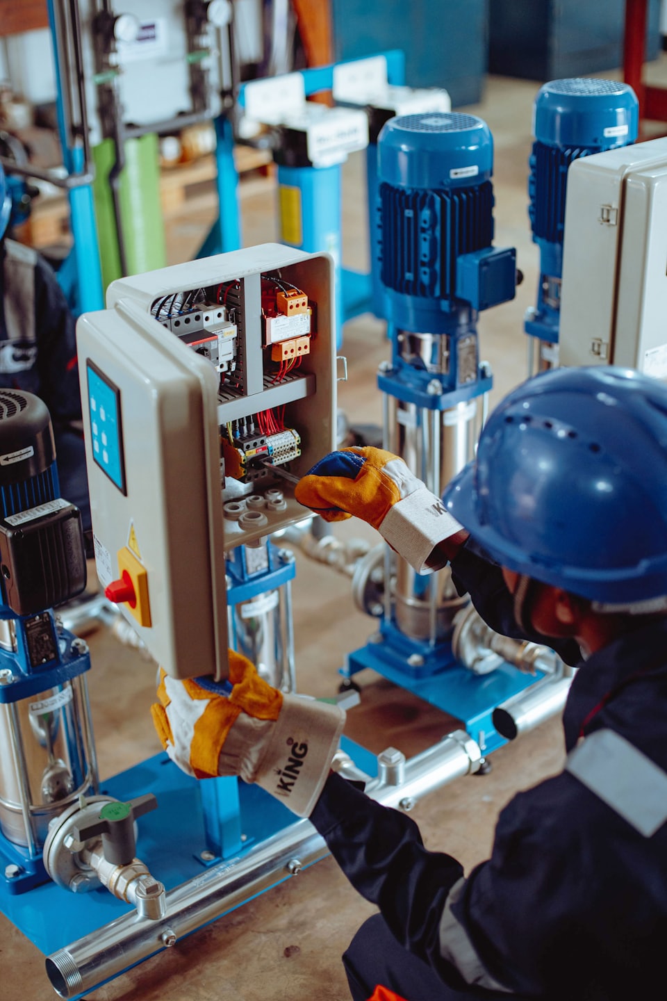 Technician works on an open electrical control panel with wires.